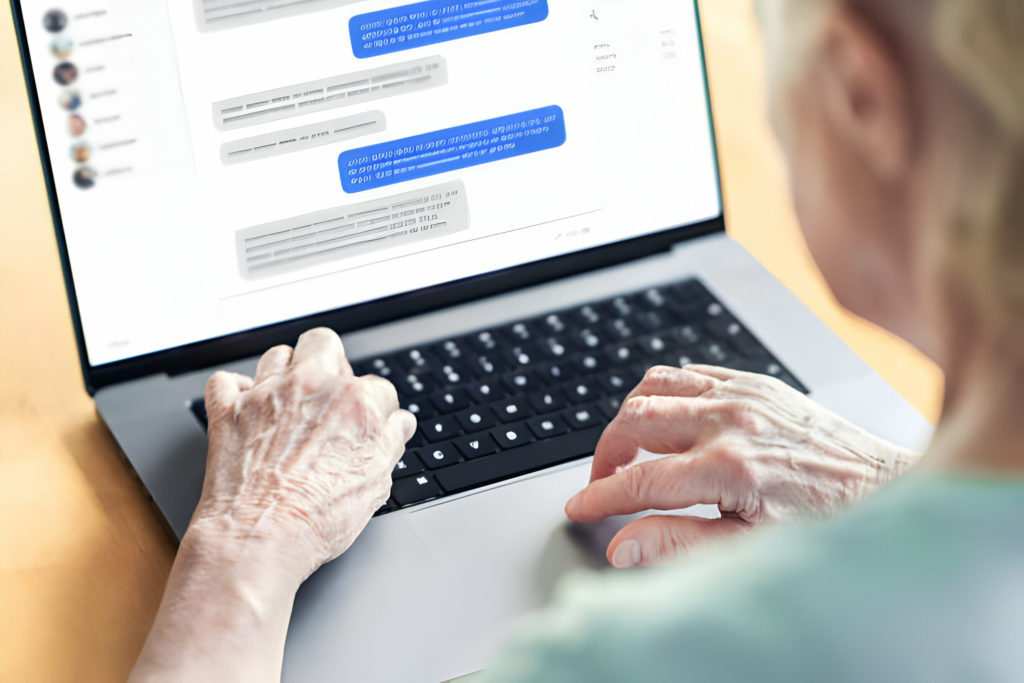 Personne âgée utilisant un ordinateur portable pour communiquer en ligne.