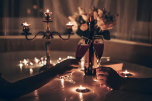 Deux personnes trinquant avec des verres de vin dans une ambiance romantique éclairée à la bougie.